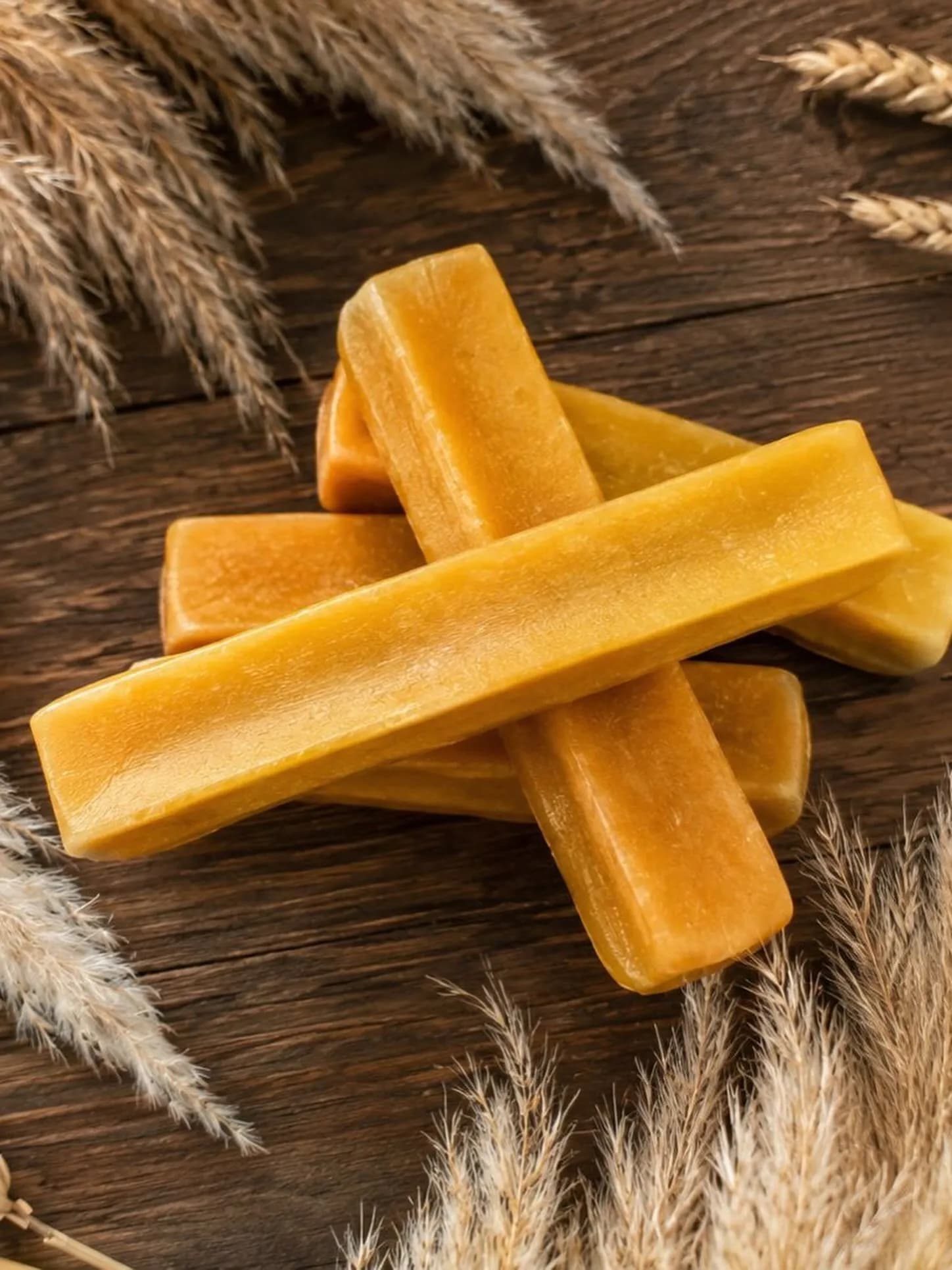 Pale golden original Himalayan yak milk chews resting on wood with dried grasses